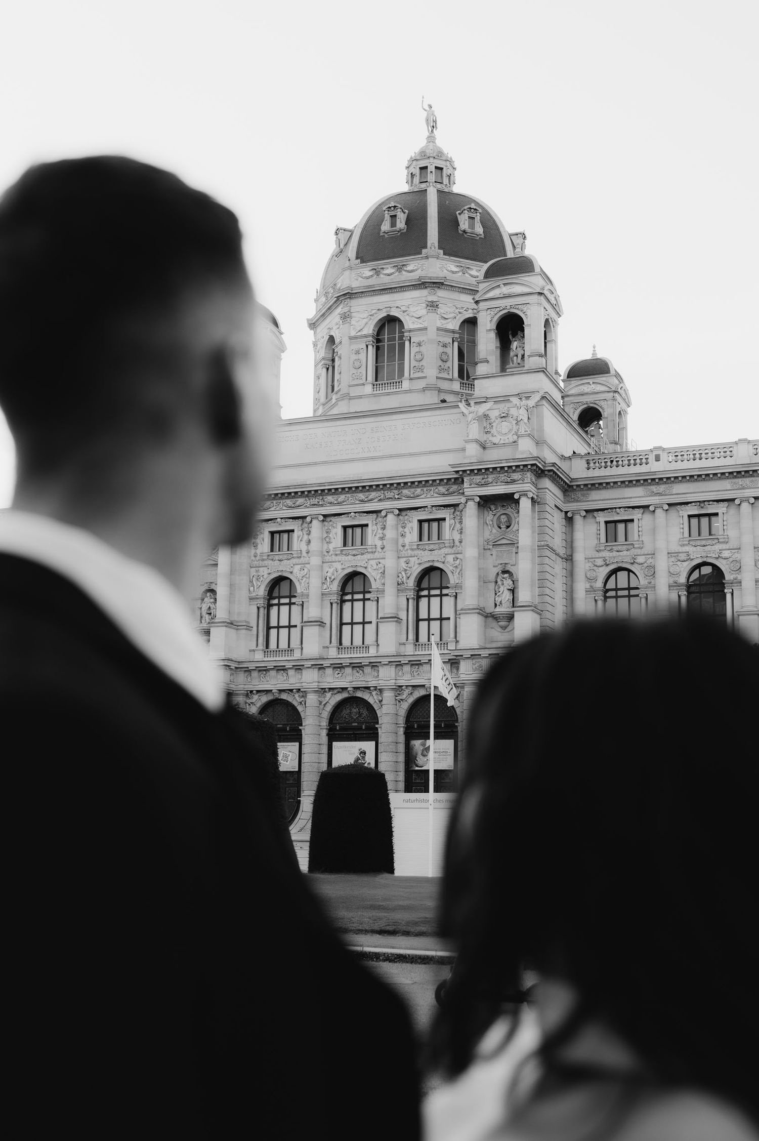 Black and white photo of a couple gazing at a grand European museum building with a domed roof.