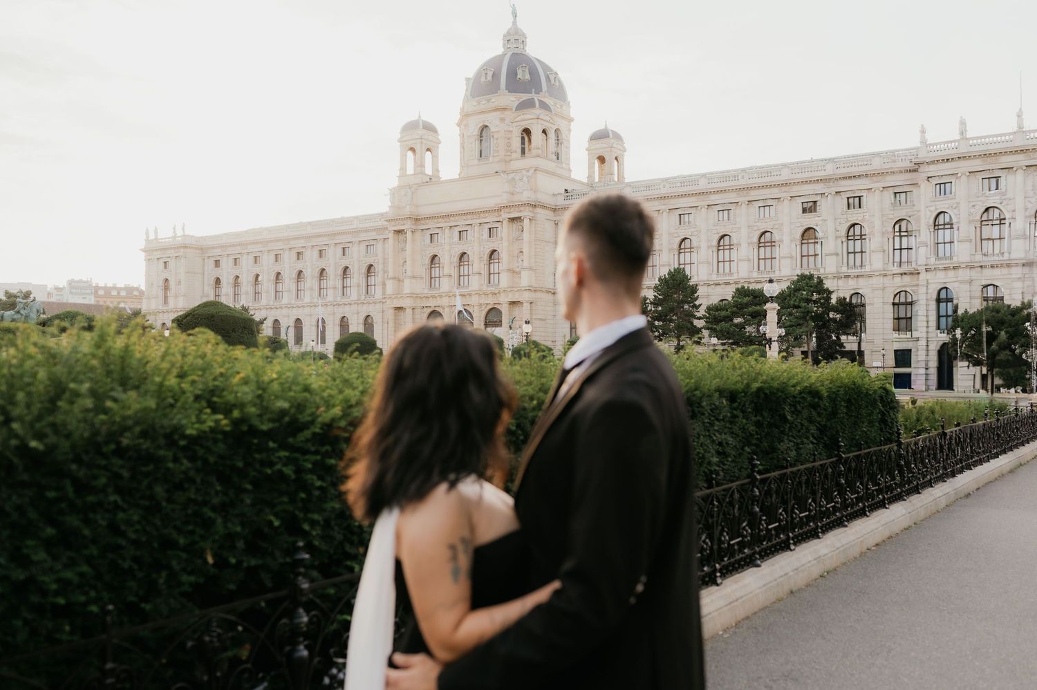 Couple embracing before grand European museum building with ornate facade and dome in Vienna.