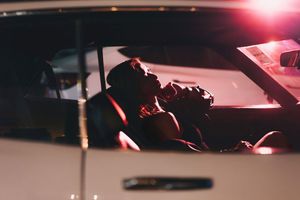 Couple sharing a romantic kiss inside a classic white car at night.