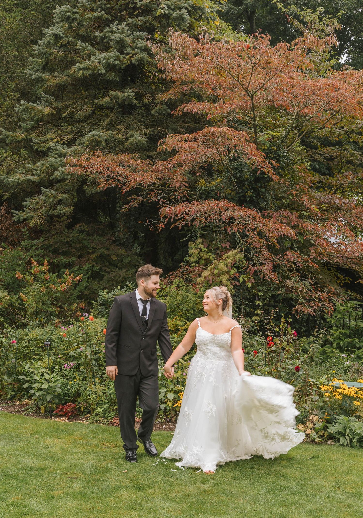 Bride and groom share a first look moment holding hands in a warmly lit industrial wedding venue with string lights.