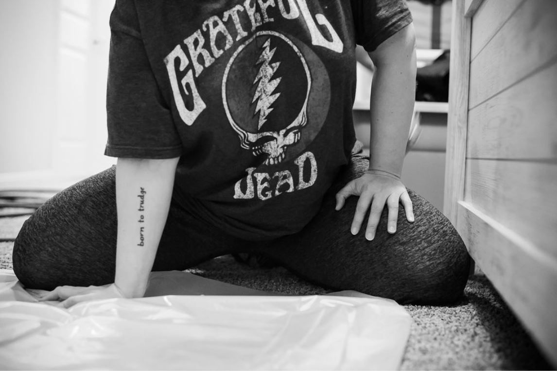 A laboring mom wearing a grateful dead t-shirt while having a contraction on the floor