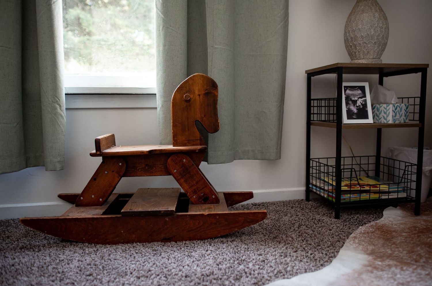 A wooden rocking horse sits in a nursery corner with natural light.