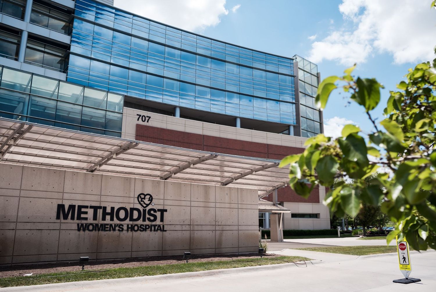 Modern glass and steel facade of Methodist Women's Hospital building on a sunny day.