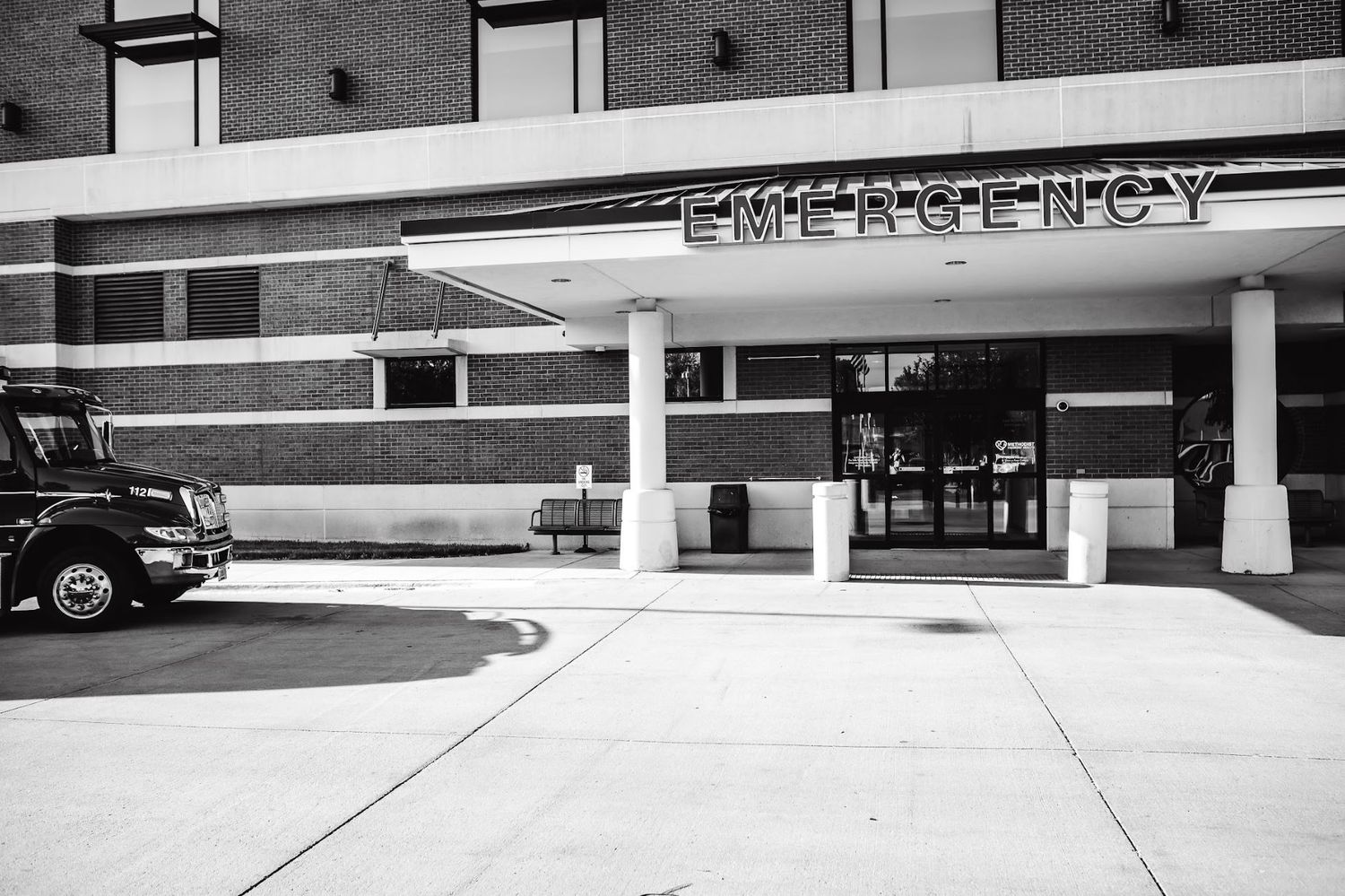 Black and white exterior view of hospital emergency department entrance.