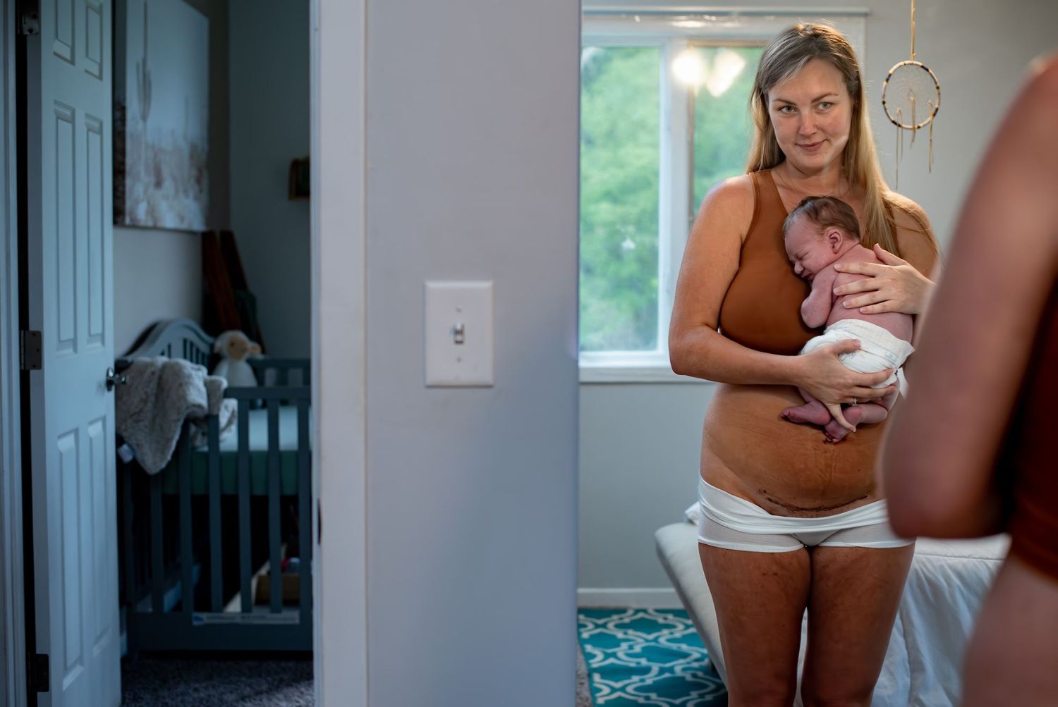 A quiet moment with a newborn baby near a sunlit window.