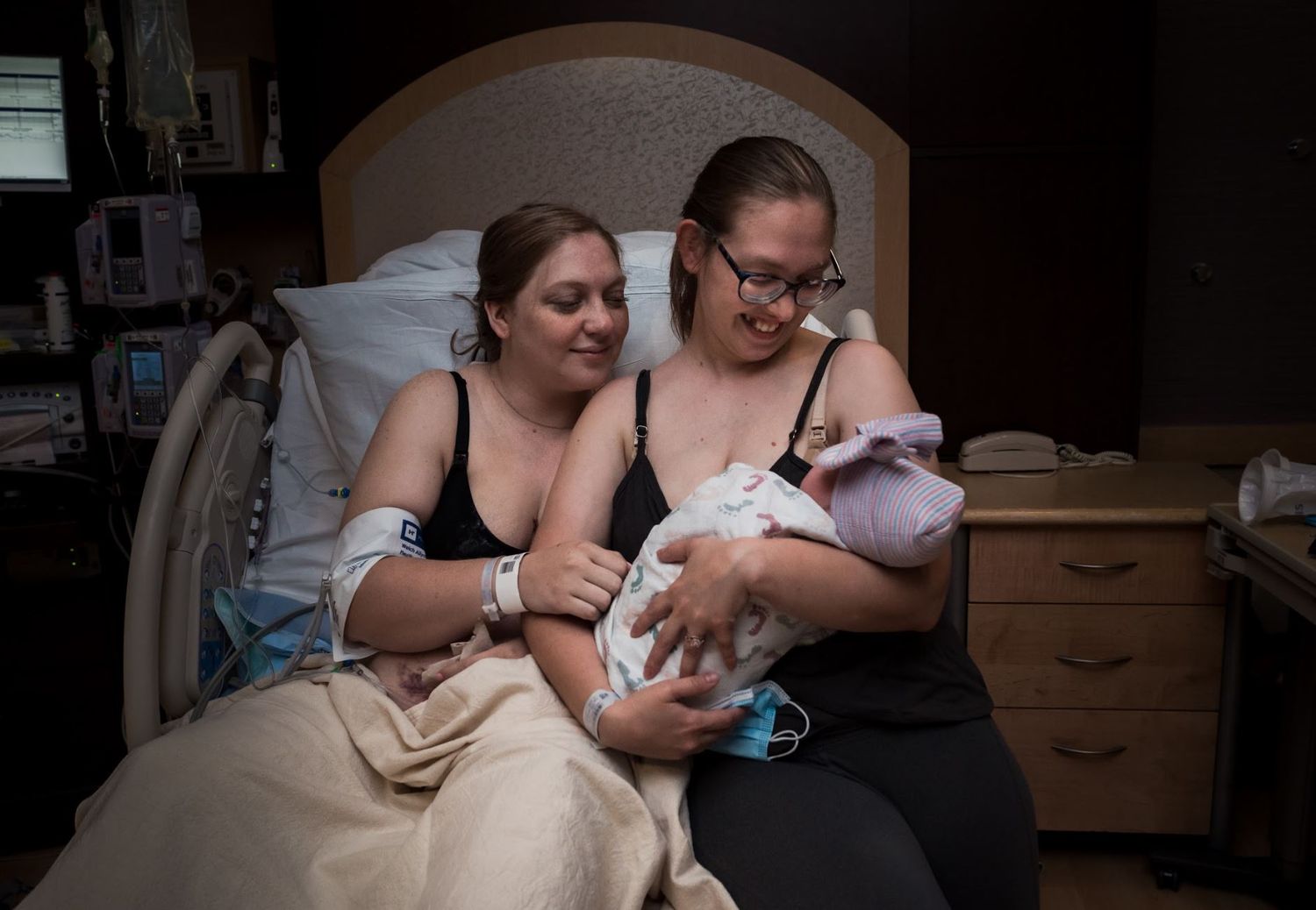 Two people share a special moment with a newborn baby in a hospital room.