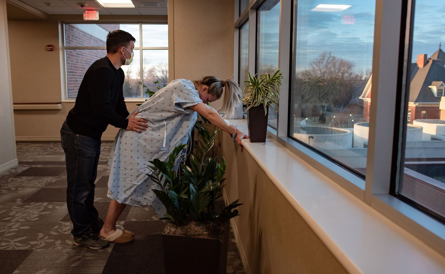 Two parents walking through Bryan Hospital corridor near windows during labor