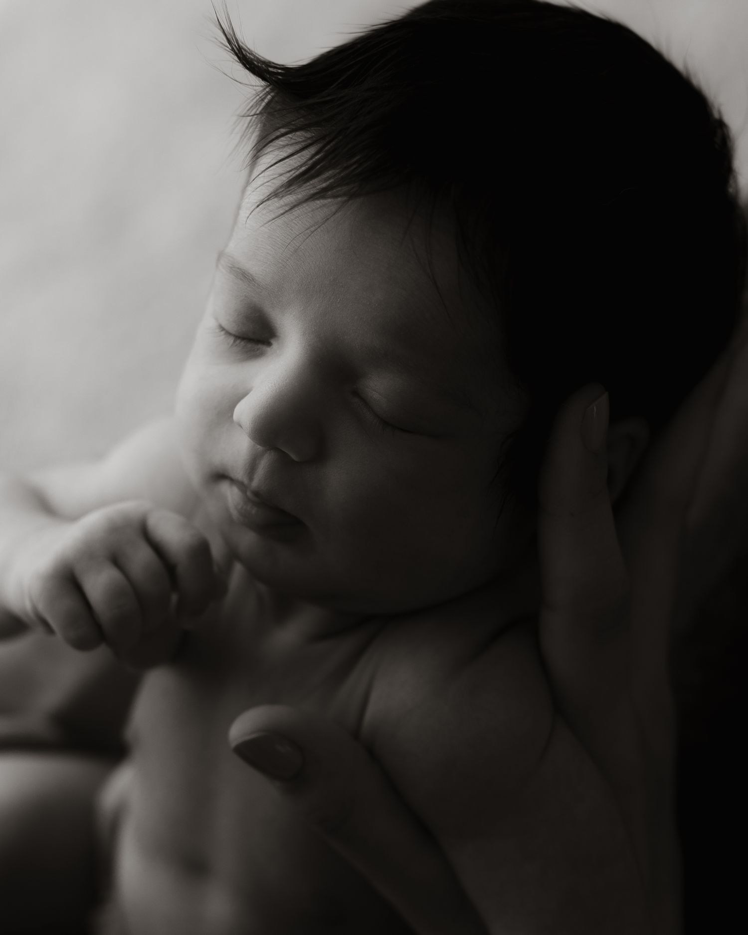 sovende baby i hendene til sin mor, svart/hvitt bilde