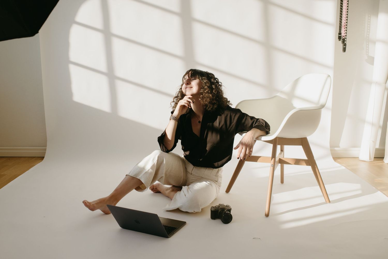 experienced event photographer in Stockholm sitting on a floor in a photo studio with her laptop and camera next to her