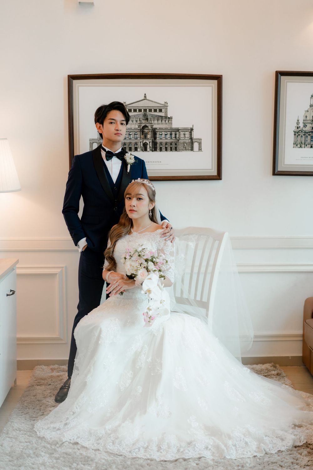 A wedding portrait in an elegant white room with architectural artwork.