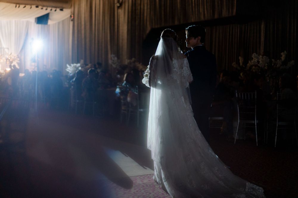 A dramatic silhouette of newlyweds dancing in a spotlight during their reception.