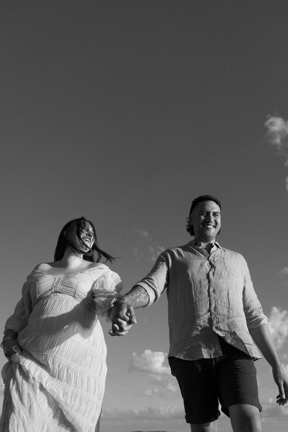 Three people in light-colored clothing dance and jump across the frame in a playful sequence against a cloudy sky.