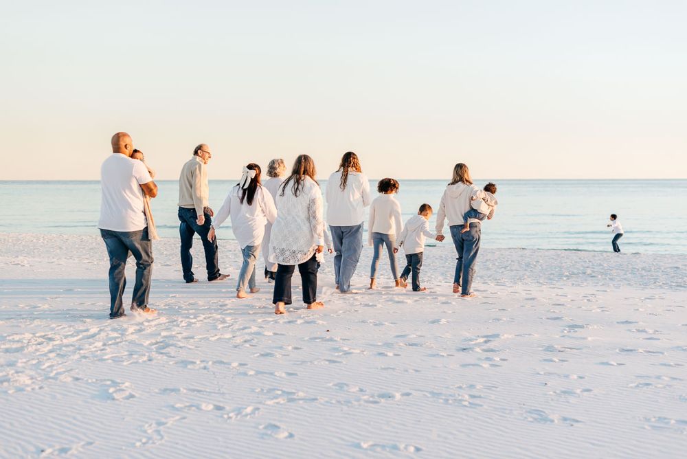 A happy family in light clothing on White sandy beaches of Destin Florida walking to the ocean.