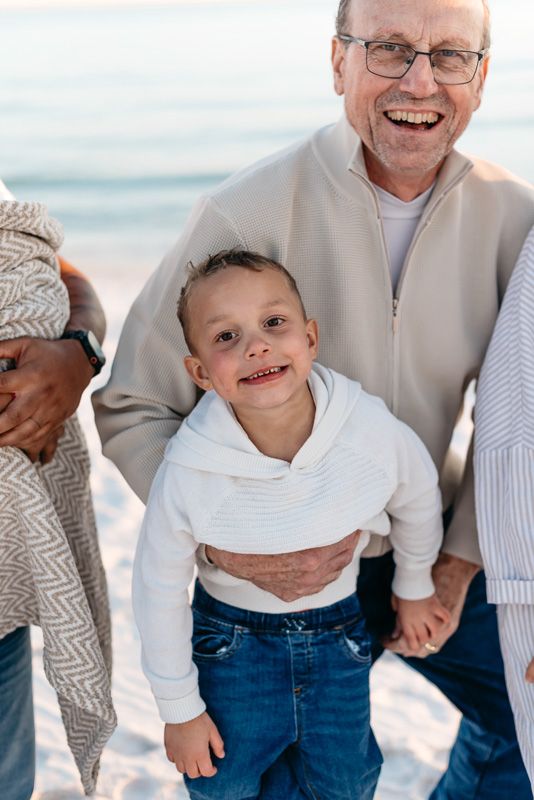 Grandpa and grandson playing on the beach with their family for the holidays in Destin Florida