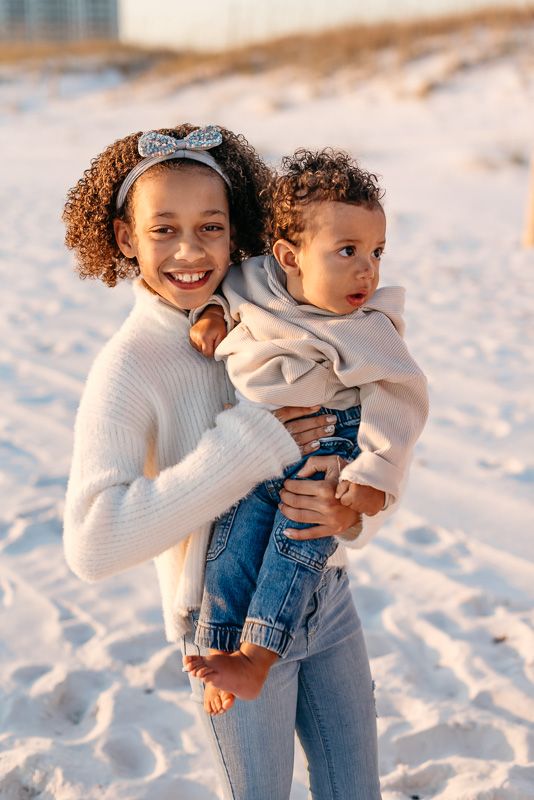 Sister holding her baby brother up for family photos with MJphotograph