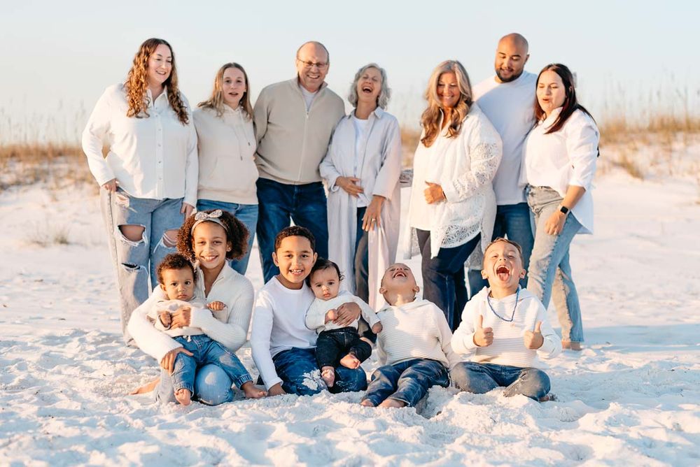 Family group laughing together as their children play in the bright white sandy beaches of Fort Walton Beach Florida.