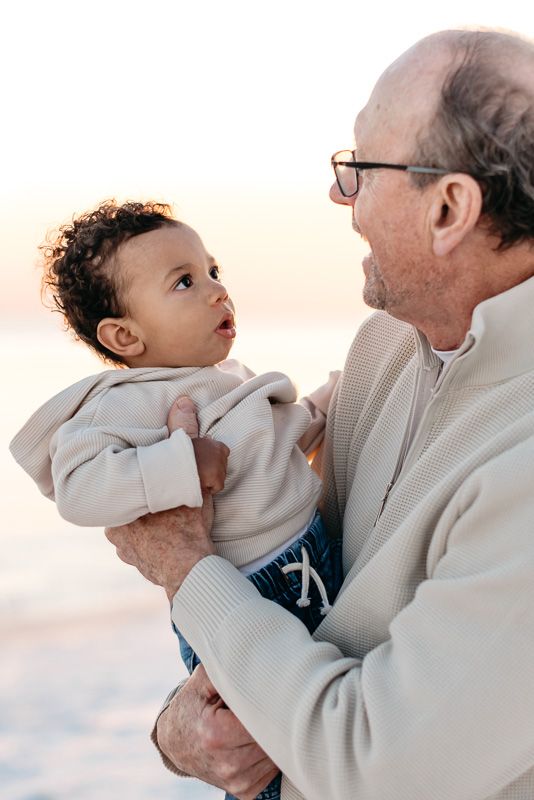 Grandpa holding his first grandson as they walk down the coastal paradise of florida