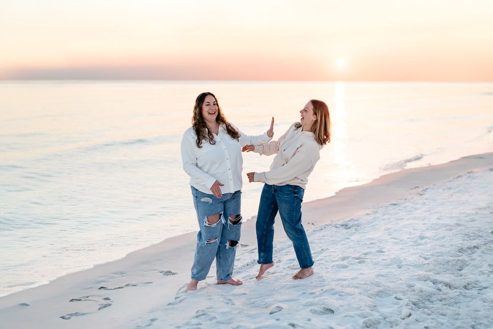 Sisters playing on the emerald coast at sunset with gorgeous golden yellow and orange hues of color.