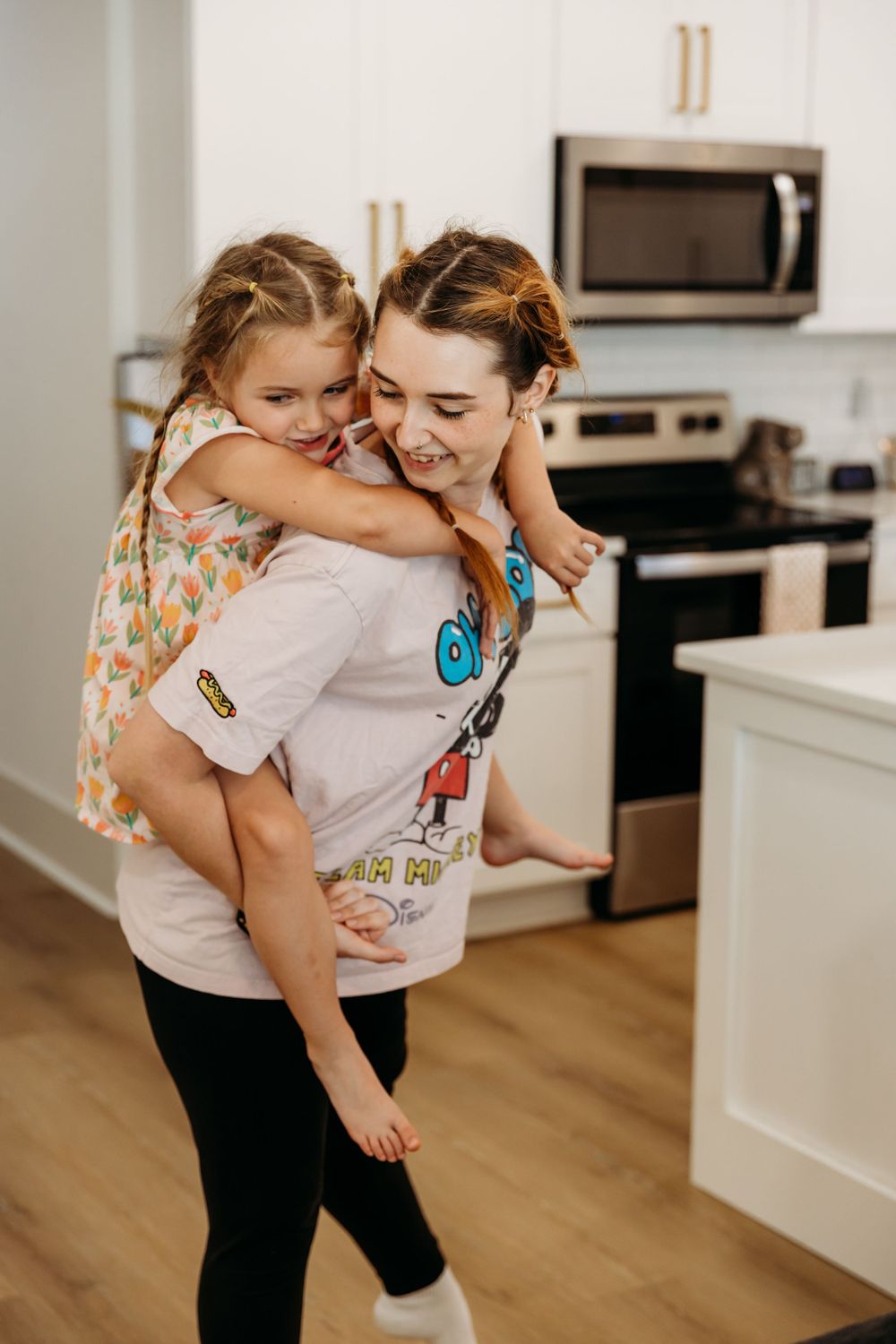 Joyful embrace in a bright modern kitchen with stainless steel appliances.