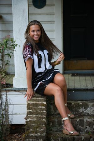 A casual portrait on white porch steps wearing a sports jersey.