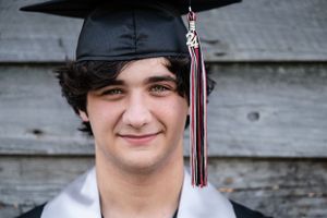 A graduate in a black cap with tassel smiles for a portrait photo.