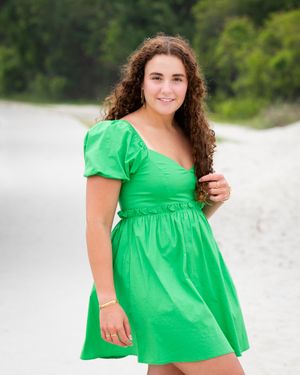 Sunny beach portrait in vibrant green puff sleeve dress against white sand.