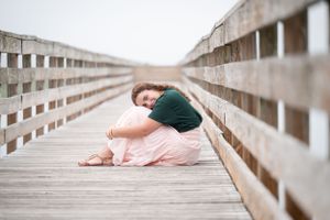 Artistic portrait on wooden boardwalk in ballet-inspired pose.