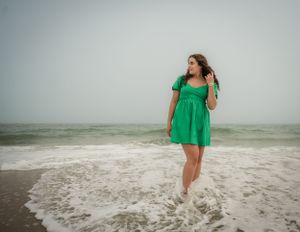 Dreamy beach portrait in emerald green dress with waves in background.