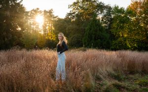 Sunset portrait in tall golden grass with sun flare through trees.