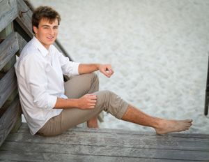 Casual portrait on wooden deck with sandy beach backdrop.