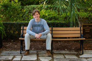 Casual portrait on wooden park bench surrounded by tropical landscaping.