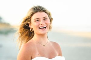 Joyful summer portrait with windswept hair at golden hour by the water.