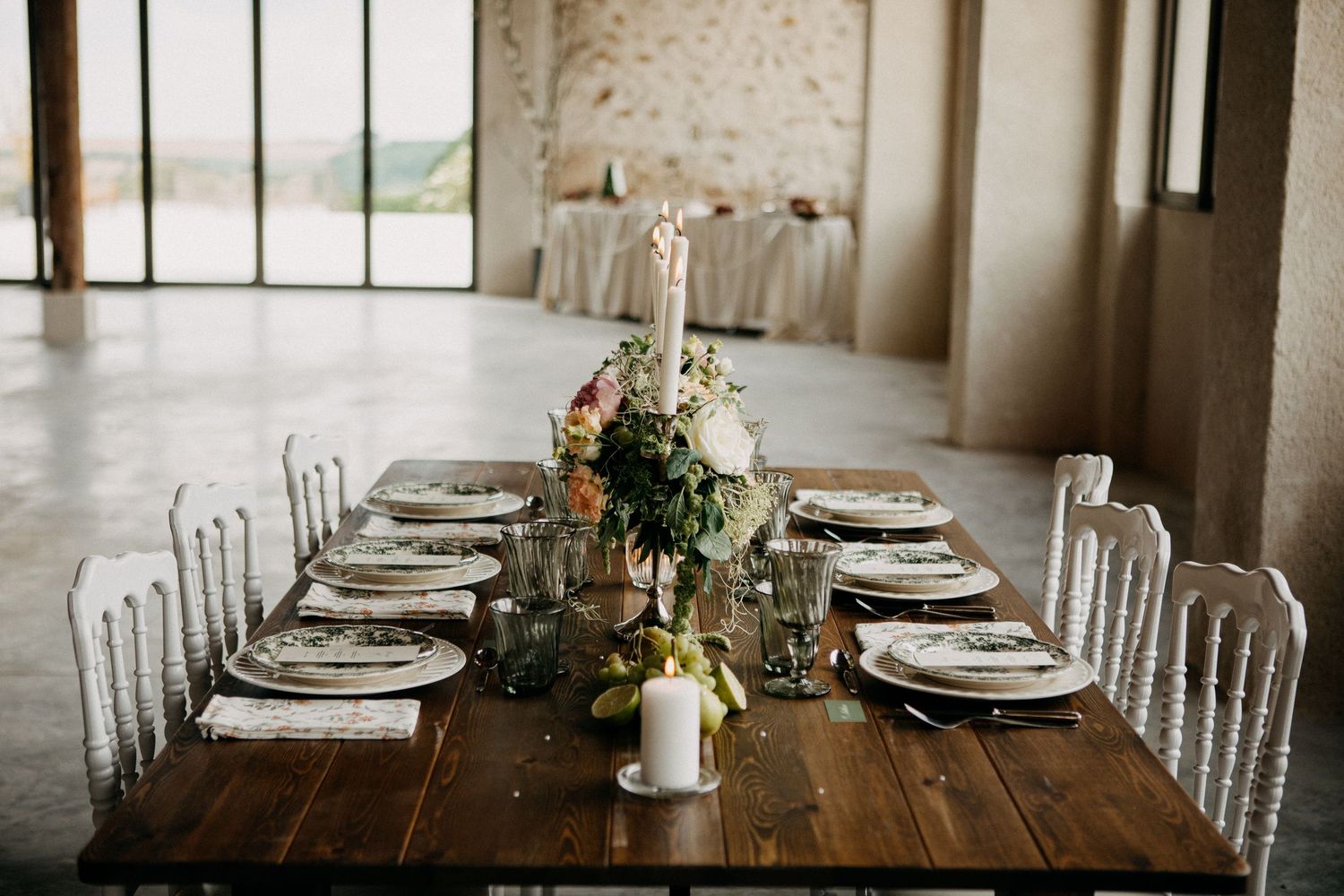 Elegant rustic wedding table set with floral arrangements and white ghost chairs.