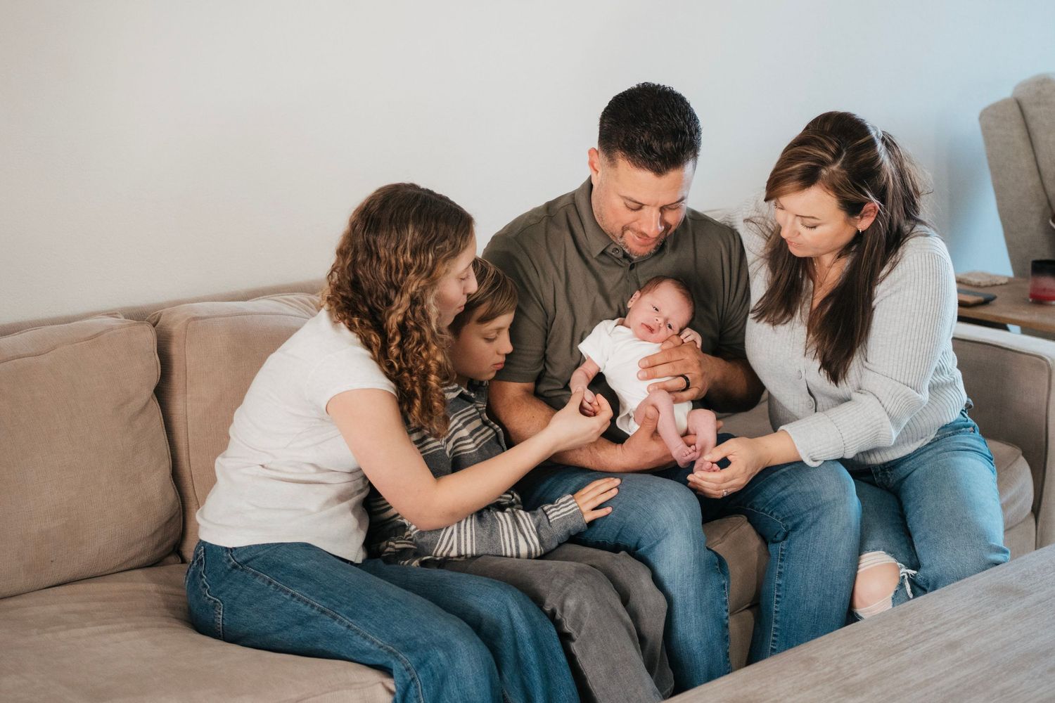 A new family of five loves on their new baby. The children adore him and mom and dad hold him