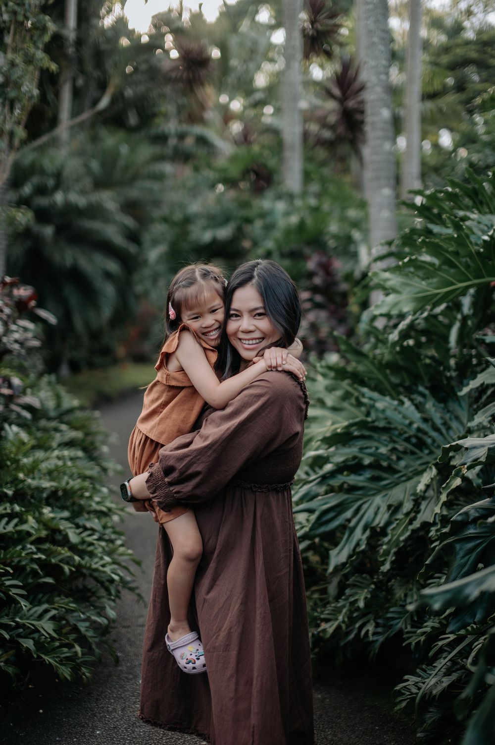 A warm embrace shared in a lush tropical garden setting with palm trees.