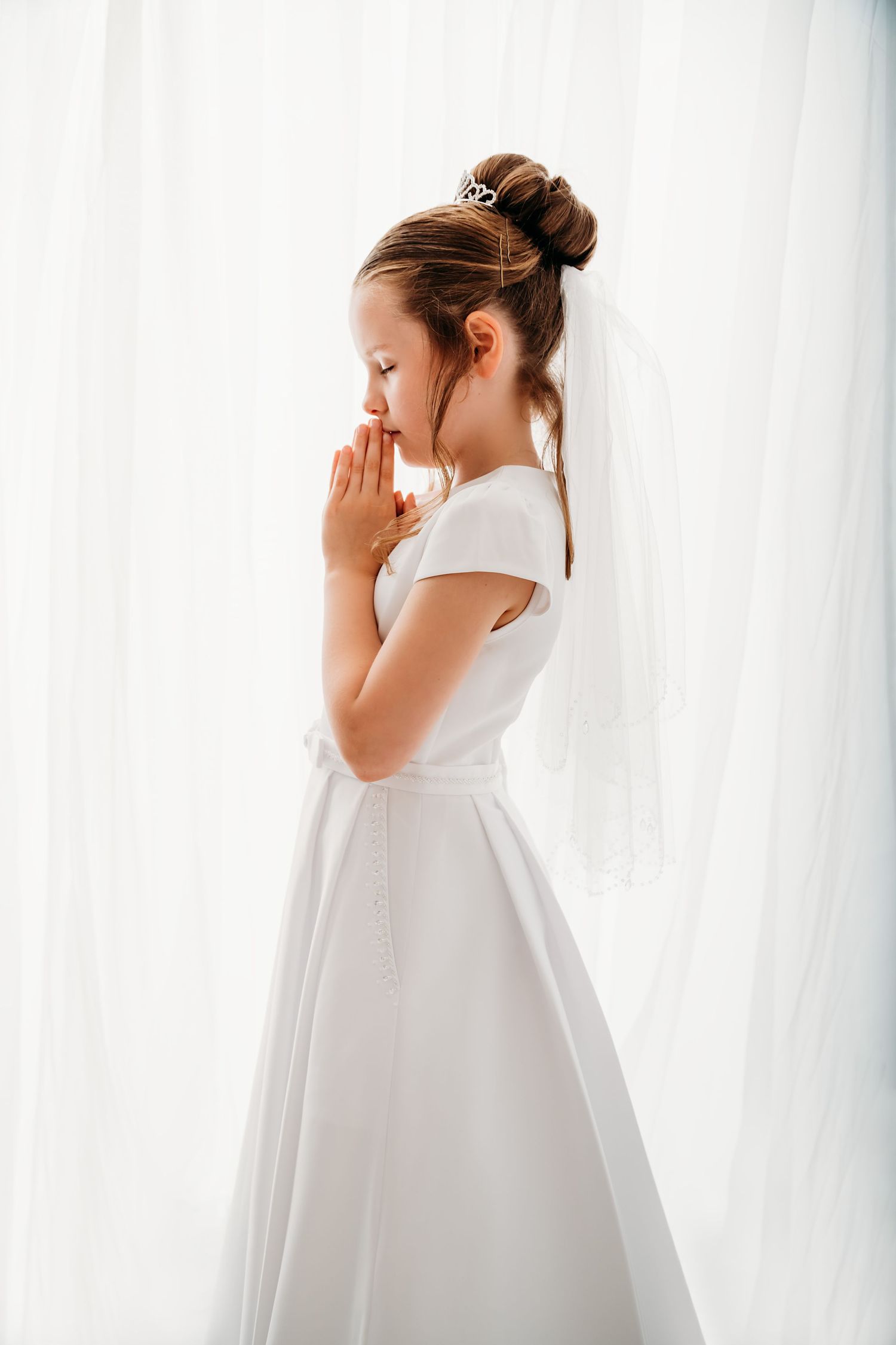 Sweet family moment captured in white studio setting with matching cream sweaters and casual denim.