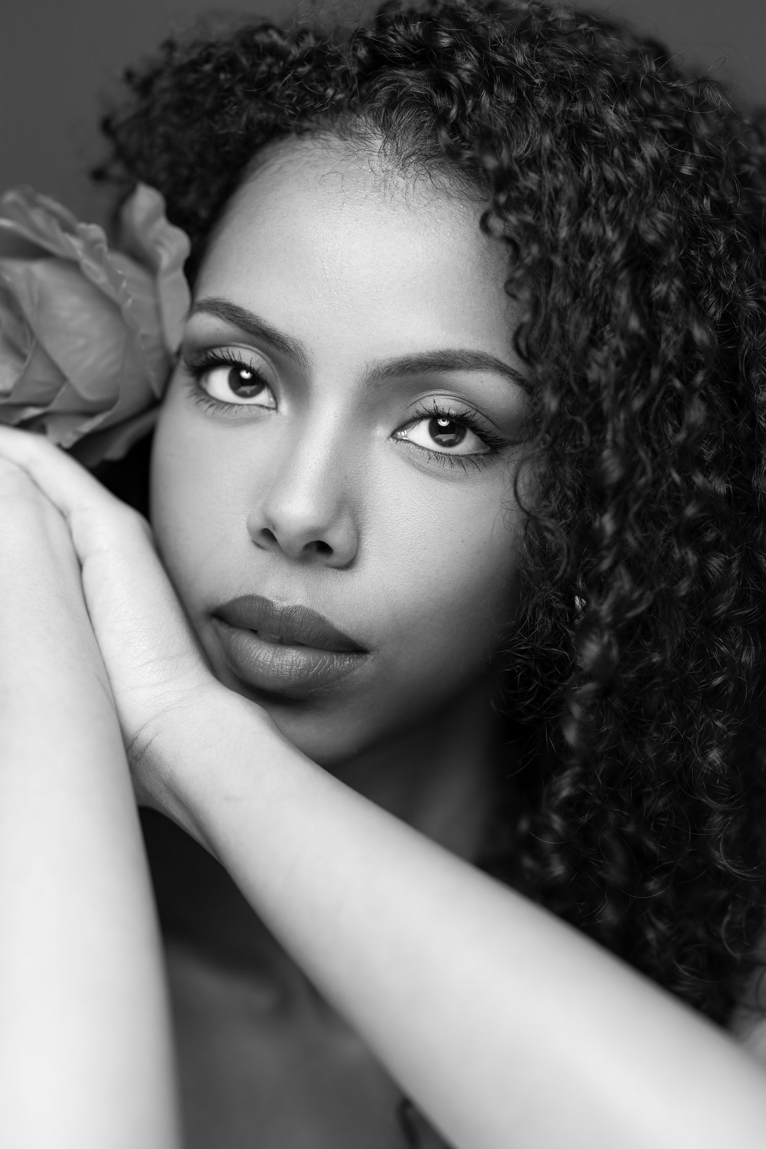 Black and white portrait photograph showing beautiful natural curly hair, expressive eyes, and elegant makeup.
