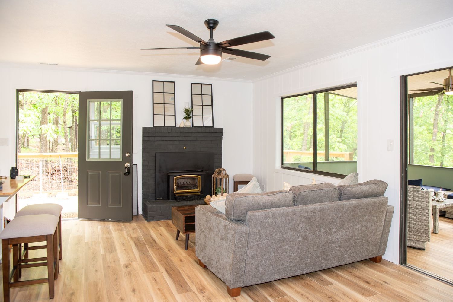 Modern living room with grey sofa, hardwood floors and large windows bringing in natural light.