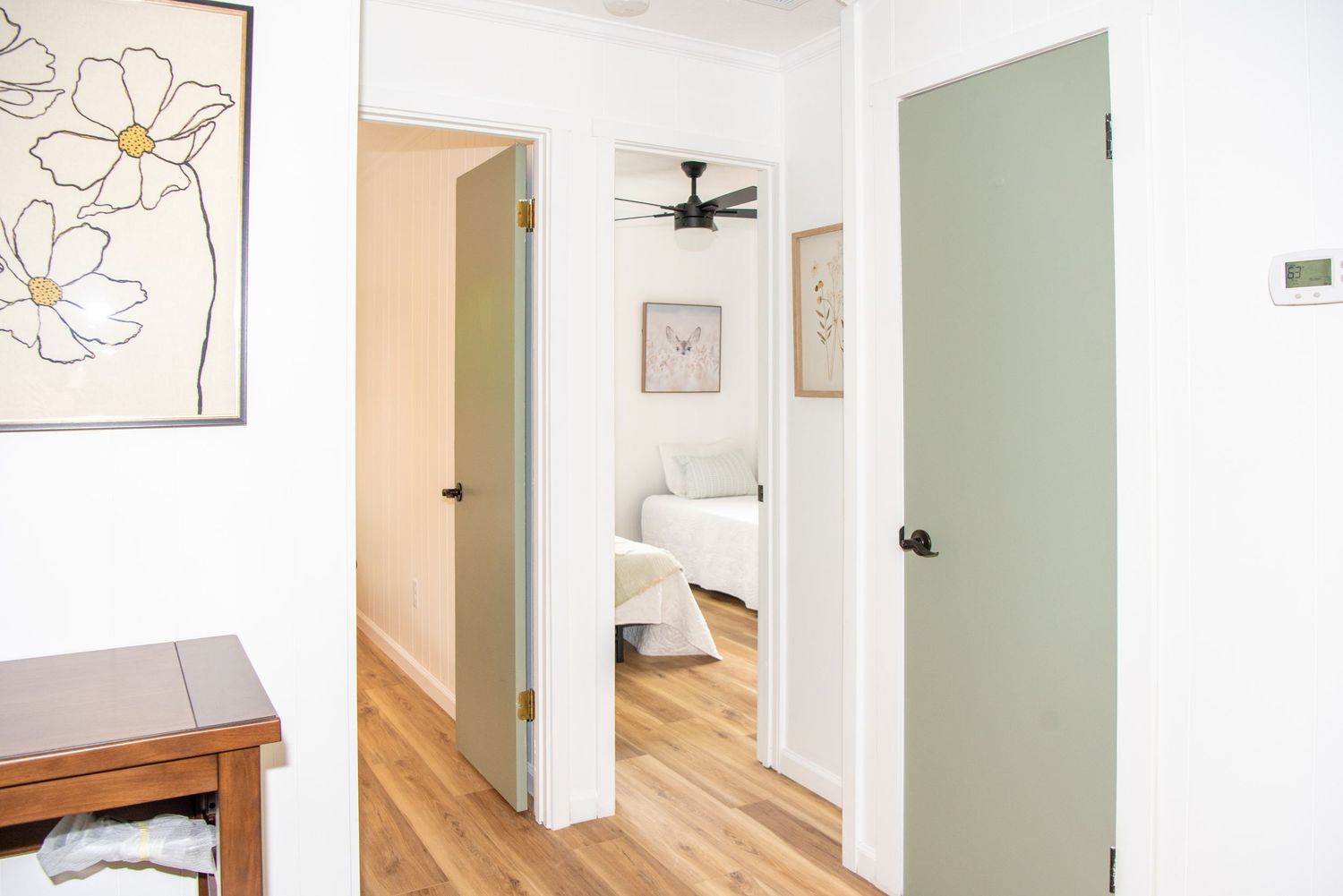 Bright hallway with white walls, hardwood floors and simple floral artwork.