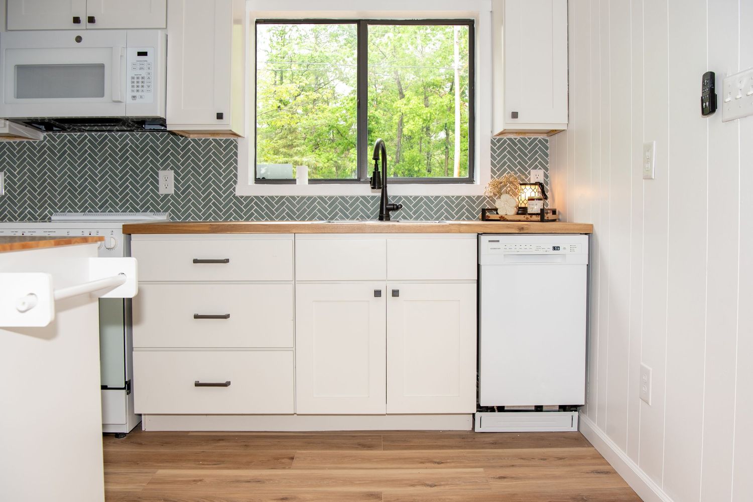 Contemporary white kitchen with butcher block countertops and black hardware against clean lines.