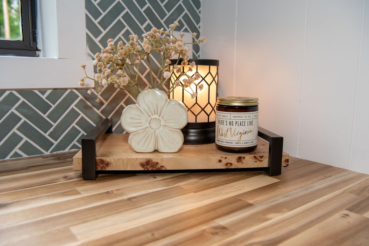 Kitchen detail showing geometric tile backsplash and wooden countertop with decorative accessories.