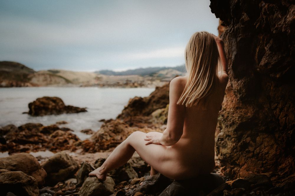 Silhouette against coastal landscape with rocky outcrops at dusk.