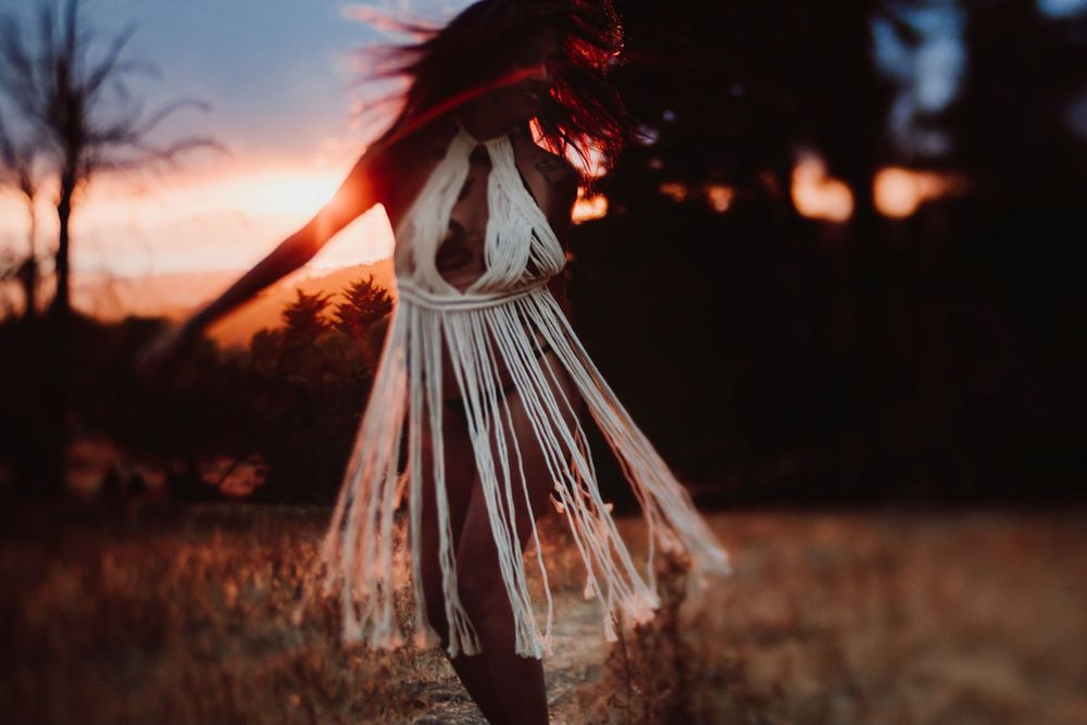 Dramatic sunset silhouette poses against a warm orange sky and dark landscape.