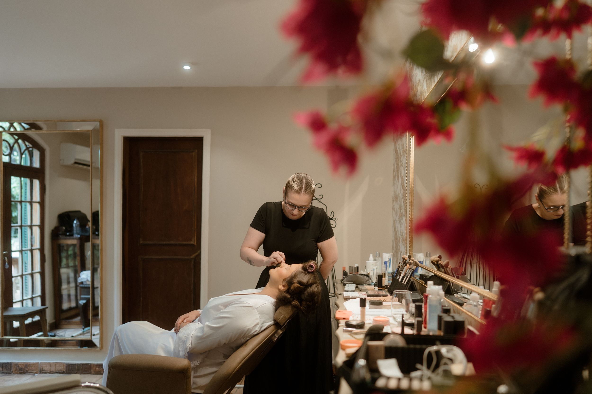 Spa treatment room with red flowers in foreground and massage setup.