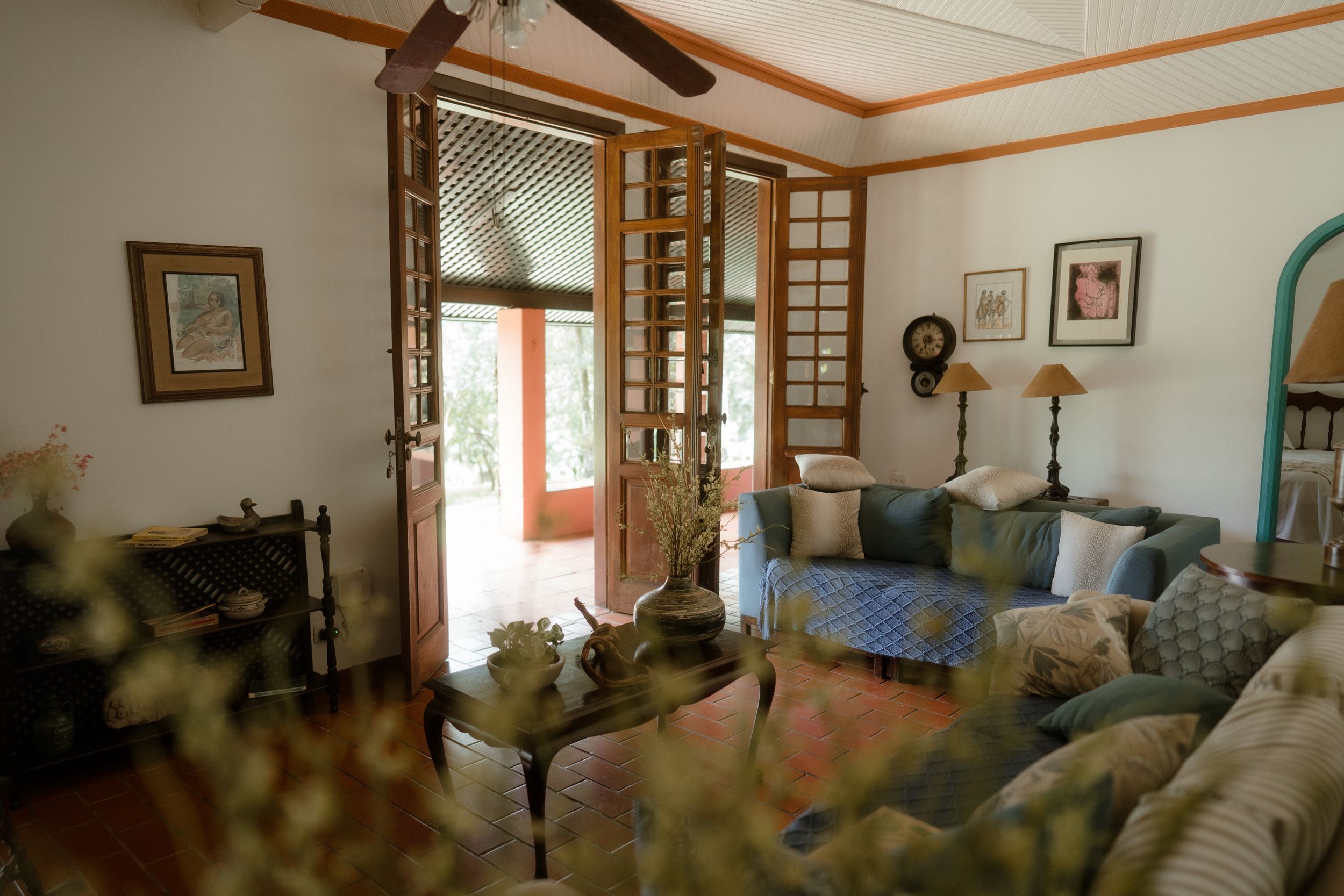 Cozy living room with blue sectional sofa, wooden shutters, and natural light streaming in.
