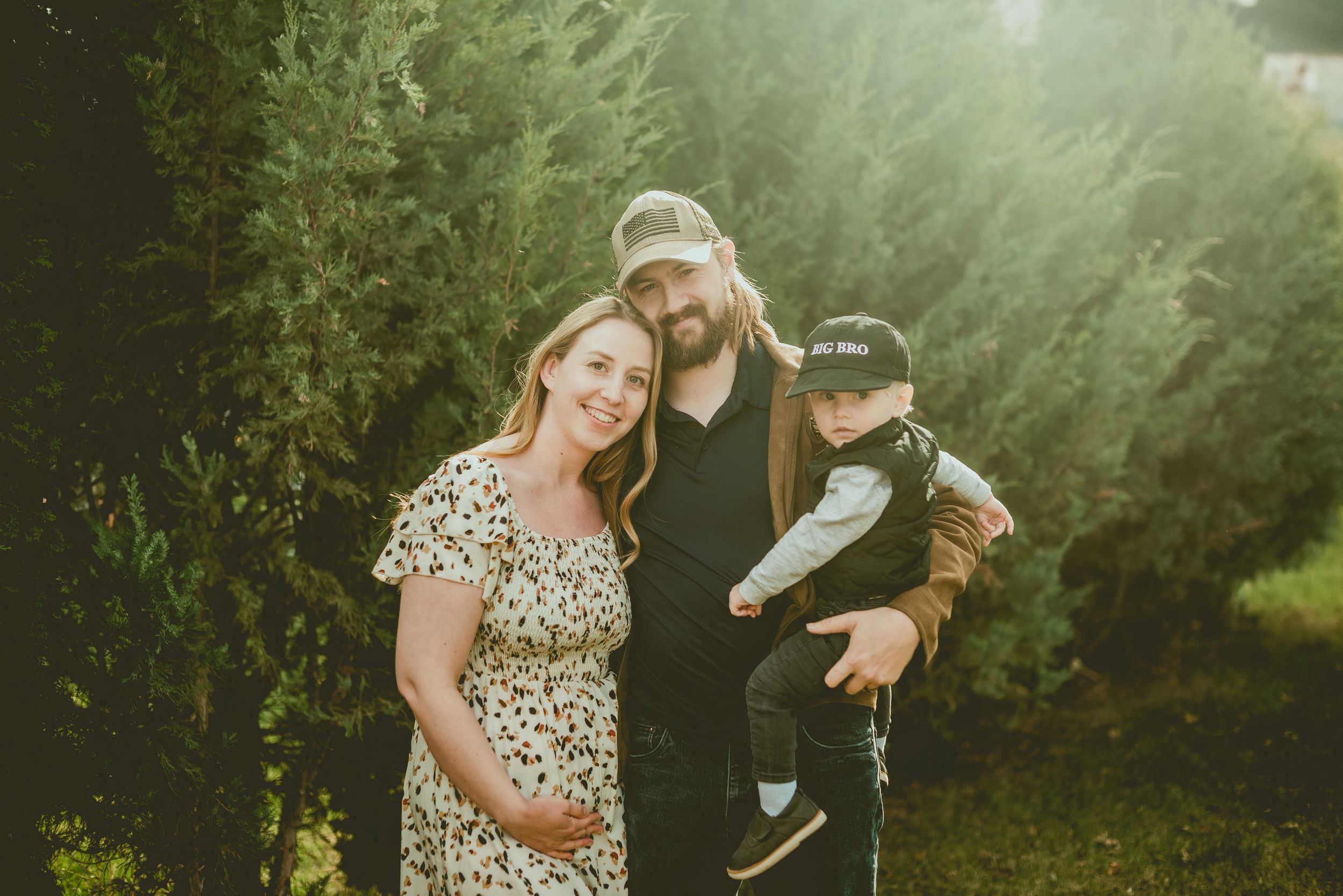 Family enjoying a tender moment together in a misty green garden setting with evergreen trees in the background.
