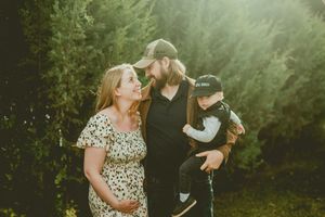 A loving family shares a joyful moment together outdoors against a backdrop of green foliage.