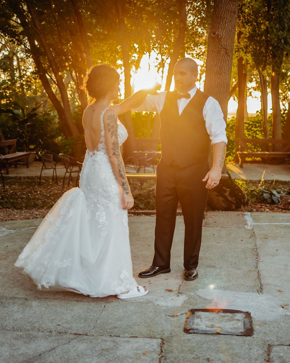 Golden sunset light streams through trees as couple shares a dance moment on outdoor patio.