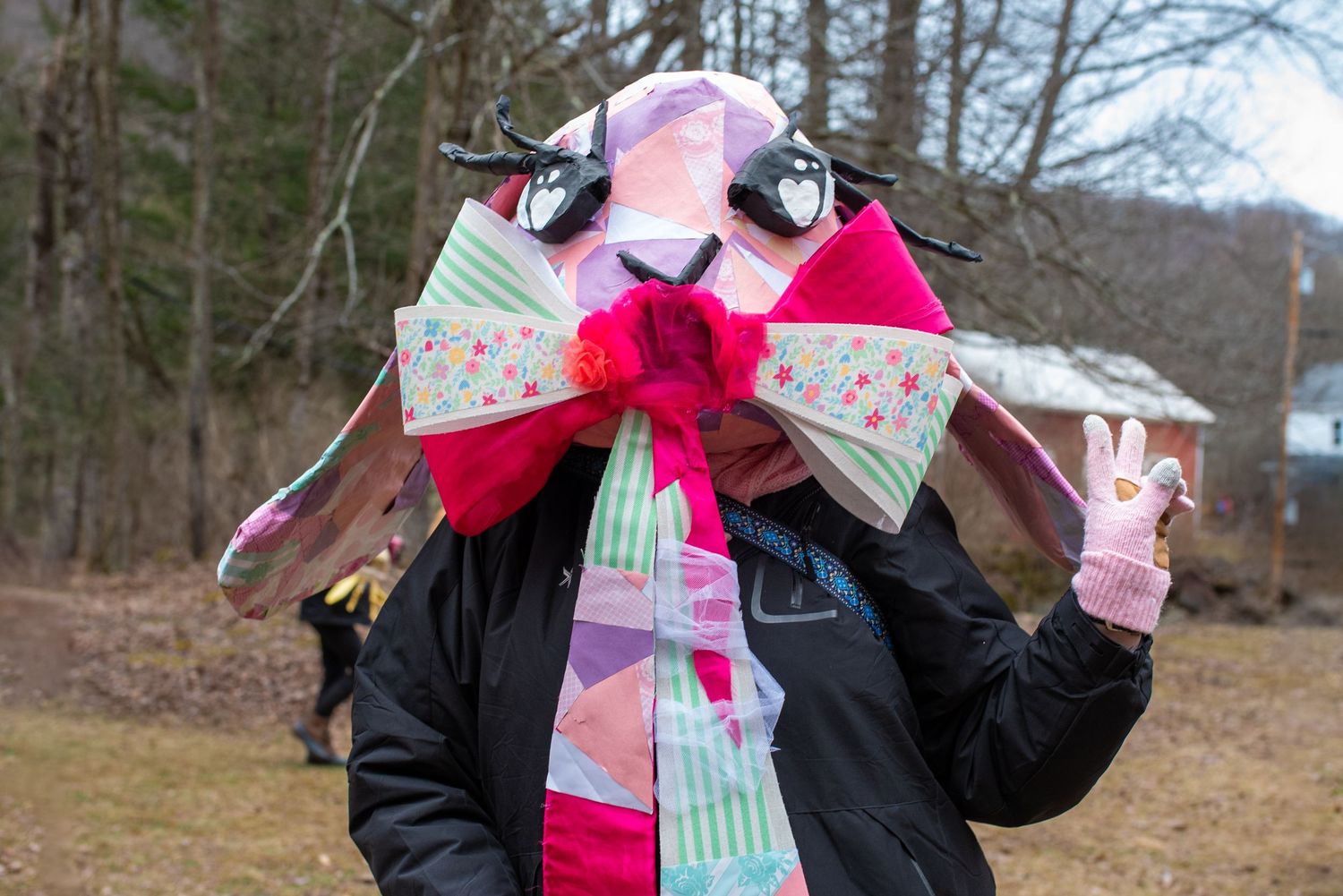 Festive figure wearing winter accessories including a large decorative bow and colorful scarf.
