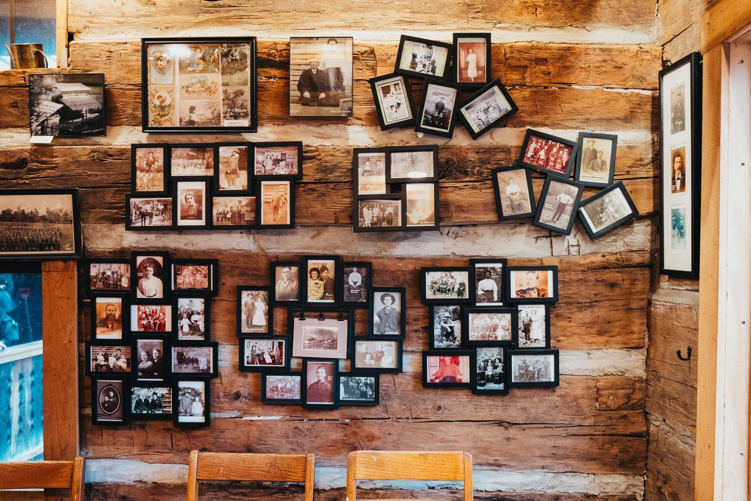 Rustic wooden wall covered with vintage family photographs in black frames.